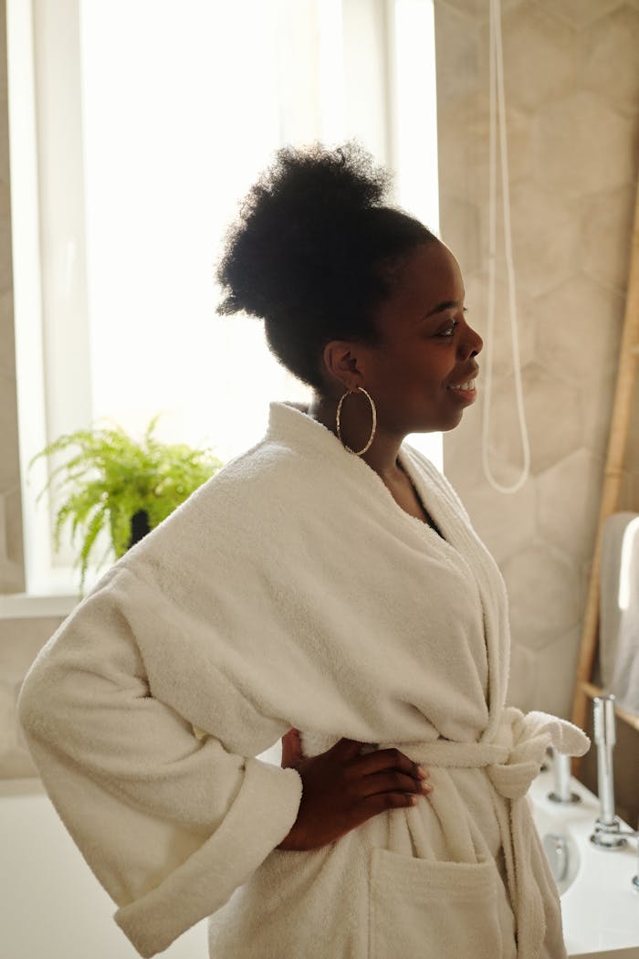 Crafting Captivating Headlines: Your awesome post title goes here A woman in a bathrobe smiling in a bathroom, enjoying a leisurely morning.
